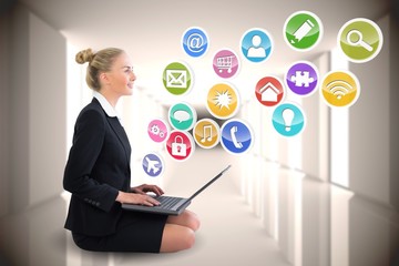 Blonde businesswoman sitting using laptop with app icons