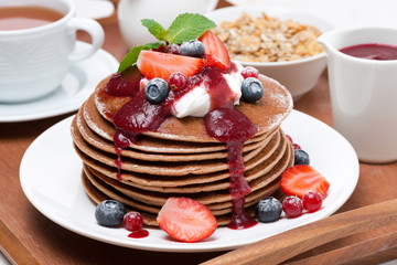 breakfast with pancakes with cream, fruit sauce, fresh berries