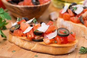 ciabatta with tomatoes, olives, parmesan on a wooden board