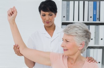 Fototapeta premium Physiotherapist assisting senior woman to stretch her hand