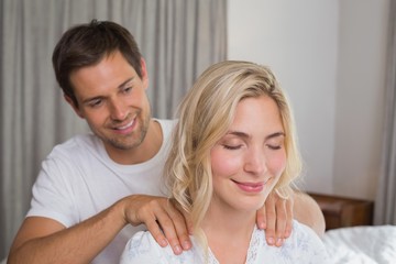 Obraz na płótnie Canvas Smiling man massaging woman's shoulders