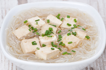 soup with rice noodles, tofu and green onions, close-up