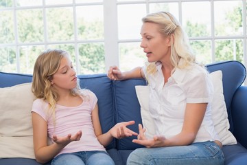 Angry mother scolding daughter on sofa