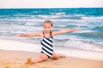 Beautiful little girl excercising on the beach