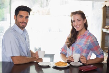 Fototapeta na wymiar Smiling couple with coffee and croissant at coffee shop