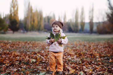 Very cheerful child having fun while tossing up leaves