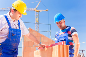 Zwei Handwerker kontrollieren Wände auf Baustelle