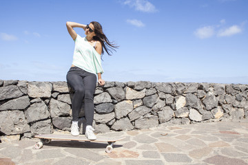beautiful young skater woman with a longboard near the sea