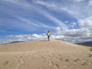 Child running up sandy hill
