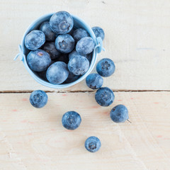 Fresh blueberries in white bowl on wood table, rustic style 
