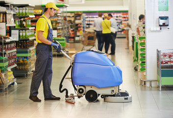 worker cleaning store floor with machine