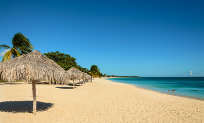 Caribbean beach with sun, palm tree umbrella, playa Ancon, Cuba - obrazy, fototapety, plakaty