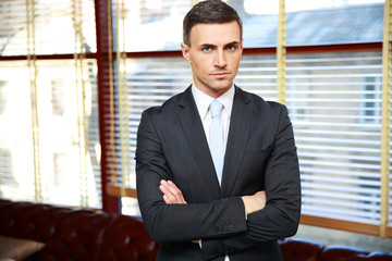 Confident businessman with arms folded in office