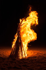 A pyre burning in the night on a beach during summer holidays.