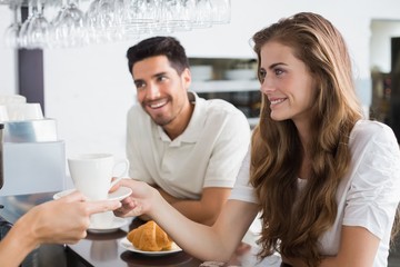 Obraz na płótnie Canvas Hand giving coffee to a couple at coffee shop