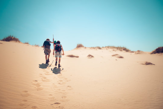 hikers climbing sand dunes - Powered by Adobe