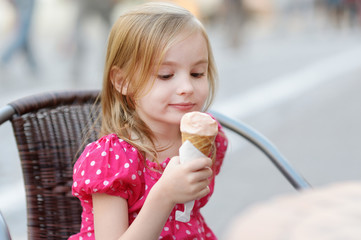 Adorable little girl eating ice-cream outdoors