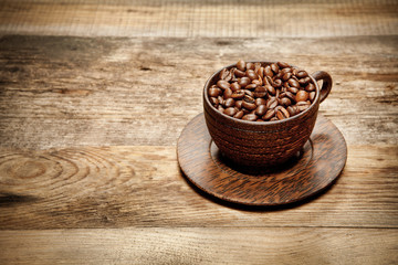 Wooden cup with coffee-beans on wooden table