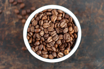 Coffee beans in bowl on brown background