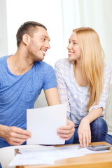 smiling couple with papers and calculator at home