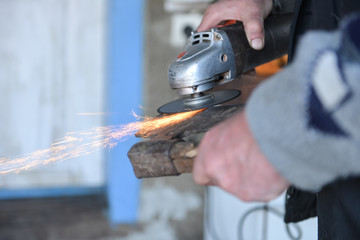 Close up of a man sharpen an ax using electric grinder. Sparks w