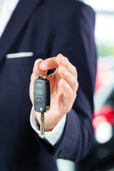 Verkäufer mit Auto im Autohaus