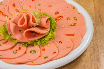 Spicy bologna in a white dish on wood tabletop © sirawut