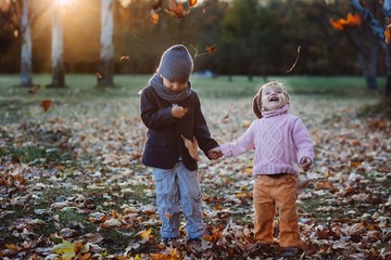brother and sister playing in autumn park leaves