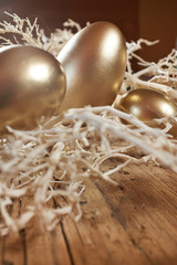 golden easter eggs in nest on vintage rustic wooden background