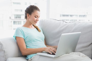 Happy woman sitting on couch using her laptop