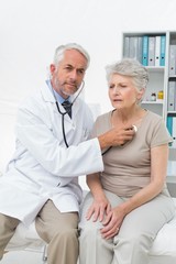 Obraz premium Doctor checking patients heartbeat using stethoscope