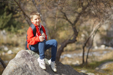 Naklejka na ściany i meble Happy smiling hiker boy with backpack in forest. Dressed in red