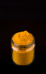 Powdered tumeric spices over black background