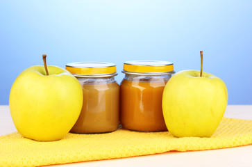 Jars of baby puree on napkin on blue background