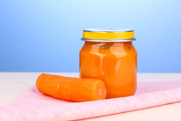 Jar of baby puree on napkin on blue background