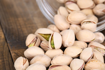 Pistachio nuts in glass jar on table close up