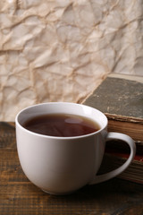 Cup of hot tea with books on table on paper background