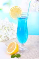Glass of cocktail on table on light blue background