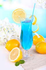 Glass of cocktail on table on light blue background