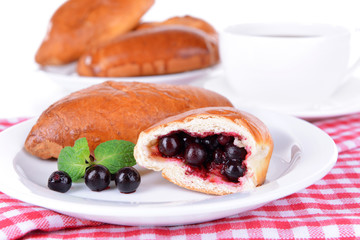 Fresh baked pasties with currant on plate on table close-up