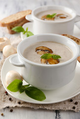 Mushroom soup in white pots, on napkin, on wooden background