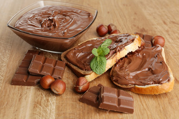 Bread with sweet chocolate hazelnut spread on wooden background
