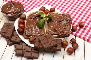 Bread with sweet chocolate hazelnut spread on wooden background