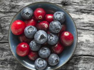 Cranberries and blueberries in blue Bowl on old wooden table