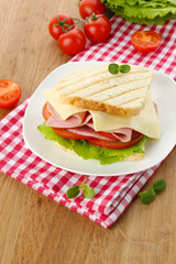Tasty sandwich with ham on wooden table
