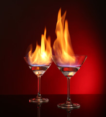 Glasses with burning alcohol on red background