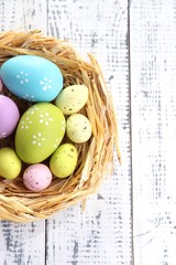 Easter eggs in nest on color wooden background