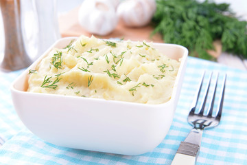 Delicious mashed potatoes with greens in bowl on table close-up