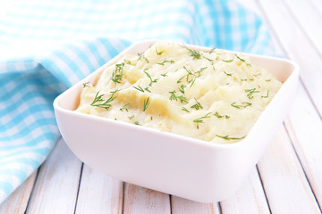 Delicious mashed potatoes with greens in bowl on table close-up