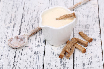 Delicate sauce in pitcher on wooden table close-up